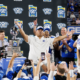 Team celebrates victory on stage with a large trophy at the Pop-Tarts Bowl, fans cheering in the foreground.