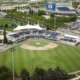 Aerial view of a baseball stadium with a striped infield, surrounding blue seating, and a large blue BYU scoreboard in the background.