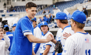 Baseball players in blue and white uniforms shake hands on the field after a game at the stadium.