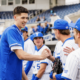 Baseball players in blue and white uniforms shake hands on the field after a game at the stadium.