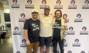 Three men posing together in front of a Huntsman Mental Health Foundation backdrop at an event.