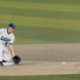 Baseball infielder in a Brighton uniform guards second base, glove ready as a runner slides in and the ball rolls toward him.