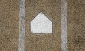 Baseball home plate embedded in a dirt infield between chalk baselines.