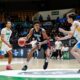 USA basketball player dribbles toward the basket while two defenders close in during a game in an indoor arena