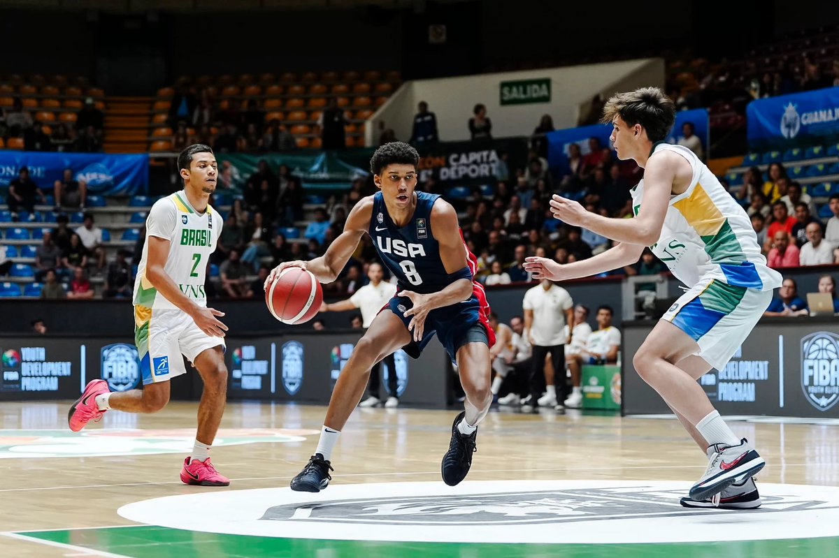 USA basketball player dribbles toward the basket while two defenders close in during a game in an indoor arena
