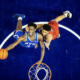 Overhead view of two basketball players contesting for the ball above the hoop, blue BYU jersey vs red jersey.