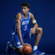 Basketball player in a blue BYU jersey (#3) dribbles a ball against a dark blue studio backdrop.
