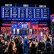 NBA Draft 2026 stage with players lined up on a red-carpet, large draft board above the crowd on screens.