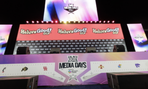 Stage set for Media Days with Heluva Good! DIP banners, colorful lighting, and a central screen above a branded front banner showing team logos.