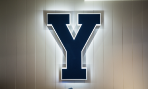 Large navy Y sign with a white glowing edge mounted on a beige paneled wall.