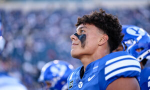 Close-up profile of a football player in a blue jersey with black eye paint, crowd blurred in the background.