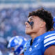 Close-up profile of a football player in a blue jersey with black eye paint, crowd blurred in the background.