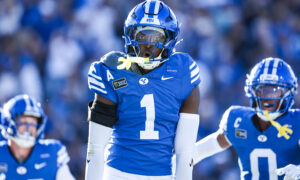BYU football player wearing blue jersey with number 1 and helmet, mid-game on the field with teammates in blue uniforms in the background