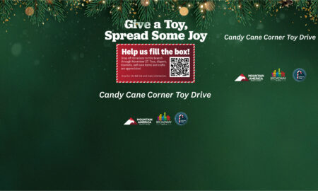 Holiday-themed banner promoting Candy Cane Corner Toy Drive: 'Give a Toy. Spread Some Joy' with a red donation box and QR code, pine garland at top, and sponsor logos along the bottom.