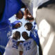Group of football players in blue and white jerseys forming a low huddle, heads together, viewed from below]
