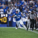BYU football player #12 runs with the ball while Notre Dame defenders pursue; crowded stadium in background.